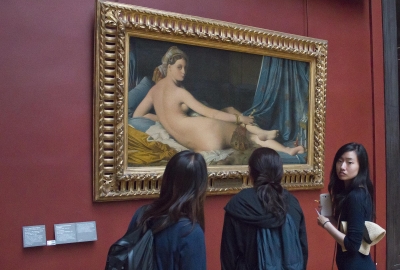 Three people standing in front of artwork of a woman