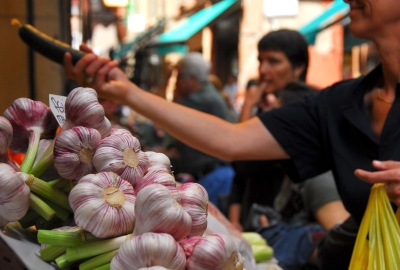 shoppers at a food market, with bulbs of garlic in the foreground