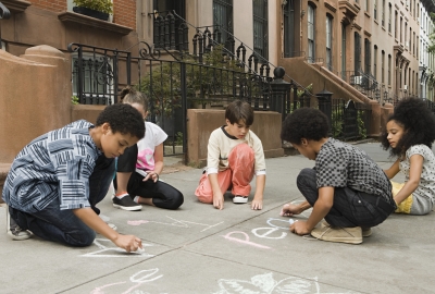Five children drawing on sidewalk with chalk