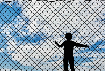 Silhouette of child behind a fence