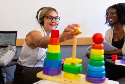 Students using audiology equipment and rainbow colored blocks.