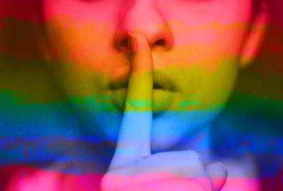 a person holding a finger over their lips to indicate silence with rainbow colors on top of the image