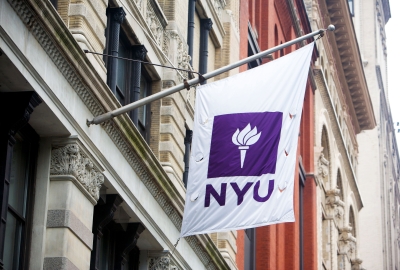 The NYU flag flying from the side of a building