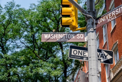 Washington Square street signs and stop lights against a backdrop of green trees
