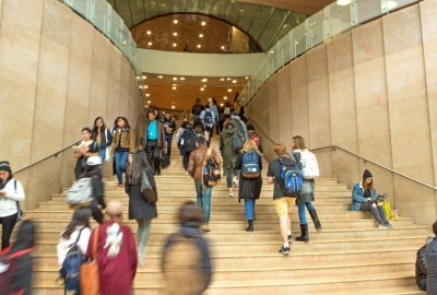Abusy scene of many students walking up and down the main stairs in Kimmel Center for University Life