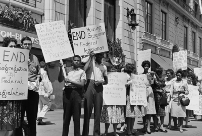 A group of mostly black protestors hold up protest signs demanding civil rights