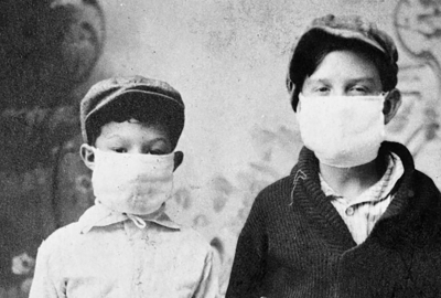 A black and white image of two young boys posing for a picture wearing masks during the Spanish flu