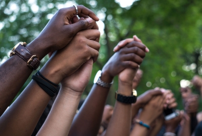a close up of several people of different backgrounds with clasped hands