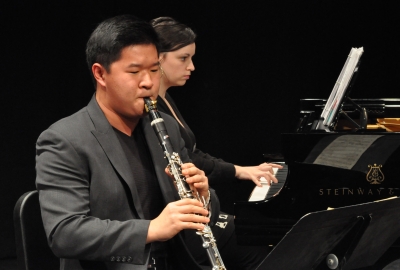 Clarinetist performing with pianist in the background