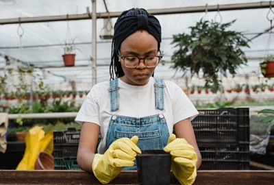 A woman in a greenhouse working with potting soil.