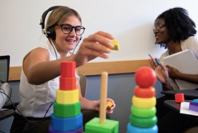 Students using audiology equipment and rainbow colored blocks.