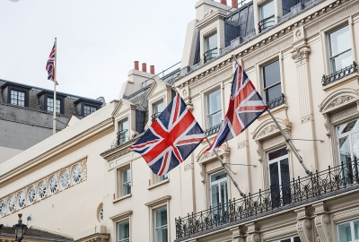 Two Union Jack flags in front of a stone building in London