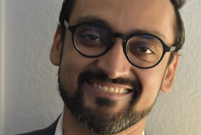 Professional headshot of Haider Fancy; smiling, wearing glasses and collared shirt 