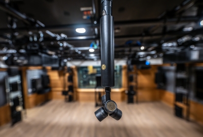 Microphone hanging close to the camera with music studio blurry in the background