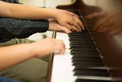 Grown up hands and a child's hand playing piano