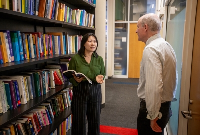 Professor Marc Scott conversing with A3SR student Nora by a bookshelf
