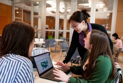 3 female student having a conversation around a laptop