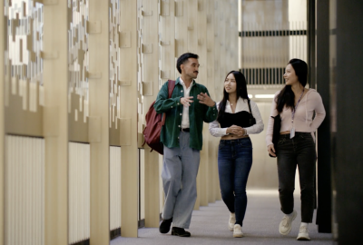 3 students walking through the halls of Bobst Library