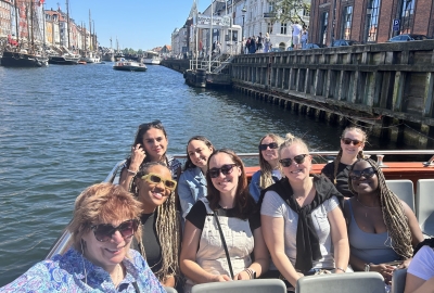 A group of students and a faculty member sit on a boat in a canal in Copenhagen