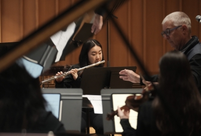 View looking through grand piano at girl playing flute