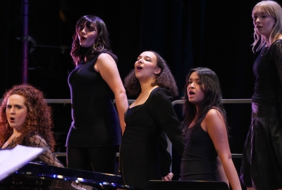 Five Choral students on bleachers singing