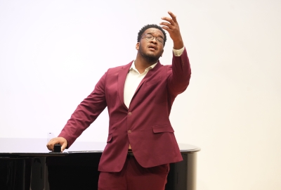 Opera singing student with arm lifted in the air during performance