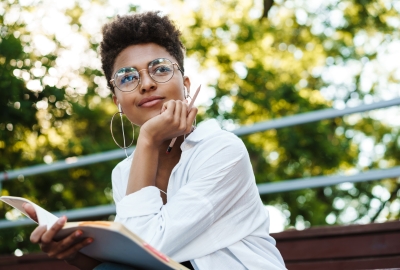 Photo of a Black woman with glasses looking thoughfully.