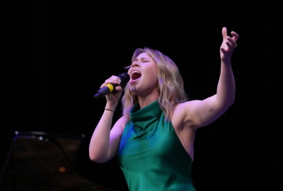 Student singing into microphone with arm up in the air