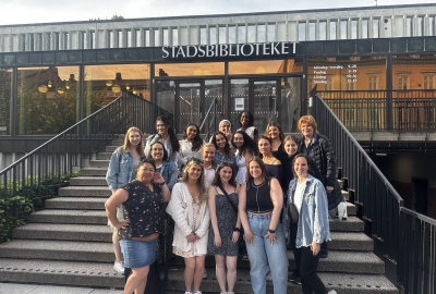 A group of students poses in front of a Swedish library building.
