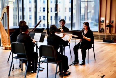 Woodwind students playing instruments in large rehearsal room
