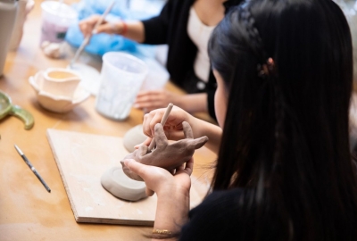 A student shapes a ceramic otter