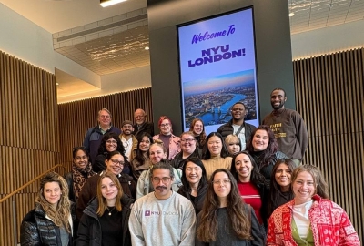 A group of VAA students stands in front of a sign reading "Welcome to NYU London!"