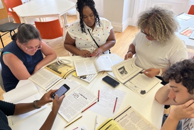 A group of students sit around a table, looking at magazines and newsletters
