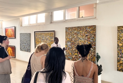 A group of students stands in an art gallery, listening to a docent