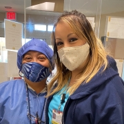 Bernadette posing with a coworker. They both wear hospital scrubs and masks.