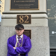 Ray Sun in violet graduation robes in front of Pless Hall