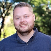 Chris Barker stands before a background of trees