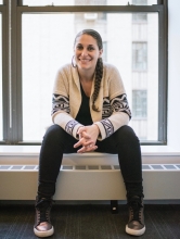 professional photo of Dr. Heather Woodley sitting on a window sill inside an NYU building