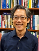 Headshot of Hirokazu Yoshikawa in front of bookshelf