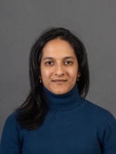 South Asian woman with black hair and a blue sweater