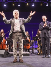 Alan Menken stands on stage and bows