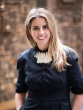 Alix is looking into the camera smiling, she's wearing a black blouse