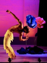Dancer doing backbend in front of large flowers with pink background