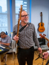 Prof Alan Turry holding guitar laughing with student