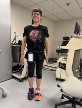 Dr. Lubetzy models the setup for a falling study. She wears athletic attire, chest and foot monitors, and a phone attached to her leg.