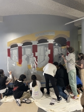 Students painting a mural in a hallway
