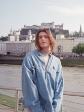 Image of advisor Luz Chavez wearing denim shirt standing in front of European looking backdrop