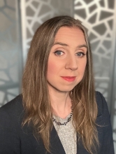 A white woman with light brown hair looks into the camera with a slight smile.