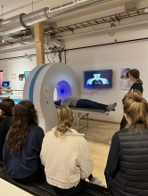 Students observe another student in a medical scanning device