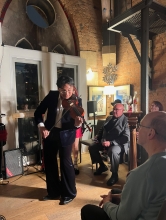 Sam Wu in a small performance space, plays the violin for an audience
